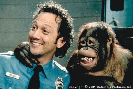 Rob Schneider in a cop uniform smiling next to a grinning monkey