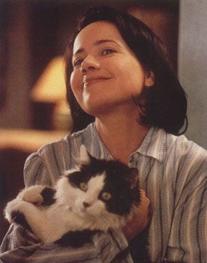 Smiling brunette woman holding up a black-and-white, long-haired cat