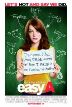 Emma Stone holding up a torn off paper with writings on it while standing in front of a black board with insults on it